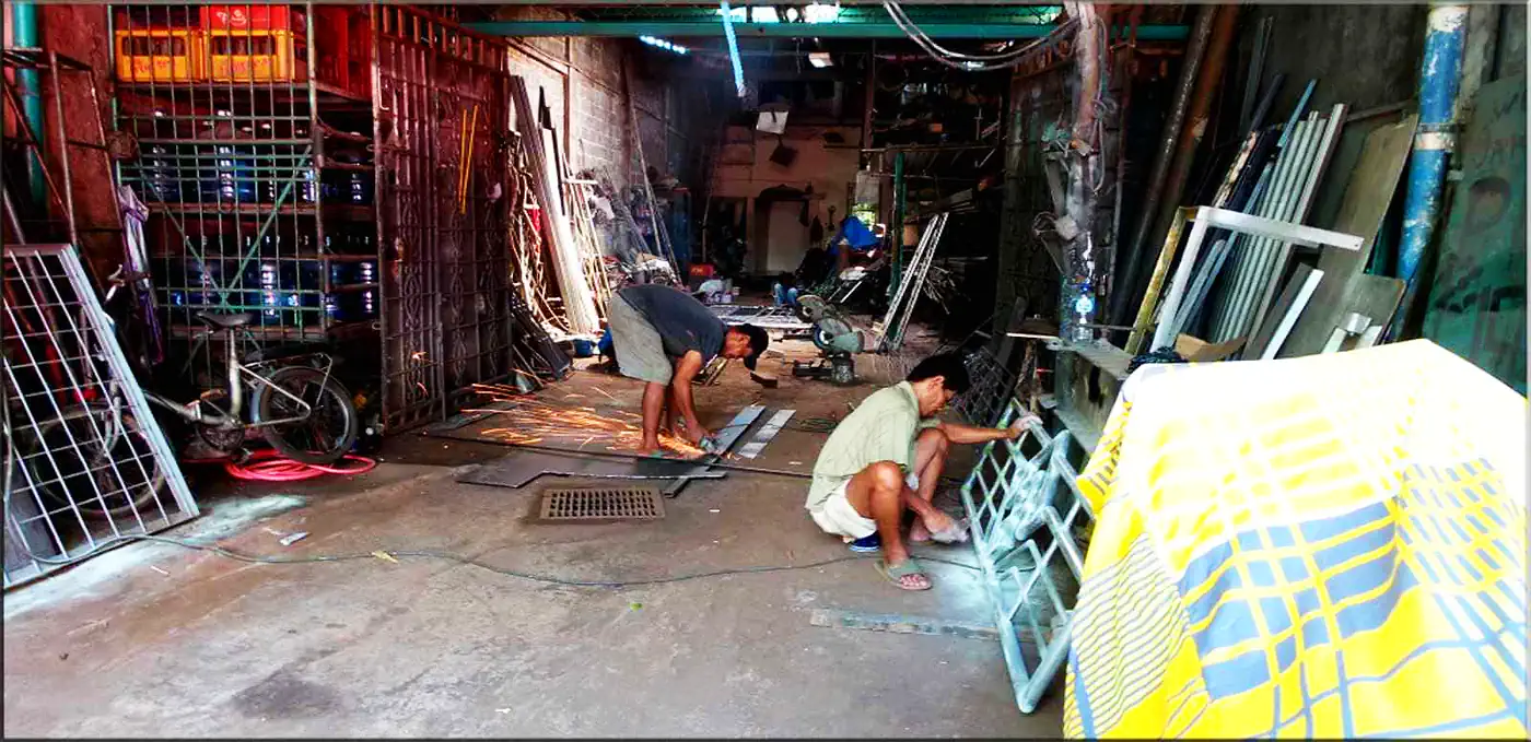Tukang las memotong besi dan merakit tralis